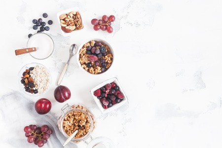 Breakfast with muesli, fruits, yogurt, frozen berries, nuts on white background. Healthy food concept. Flat lay, top viewの写真素材