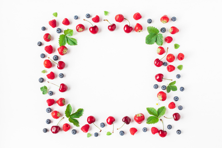 Fruits on white background. Creative frame made of fresh fruits. Strawberry, raspberry, blueberry and sweet cherry. Summer concept. Flat lay, top view, copy spaceの写真素材