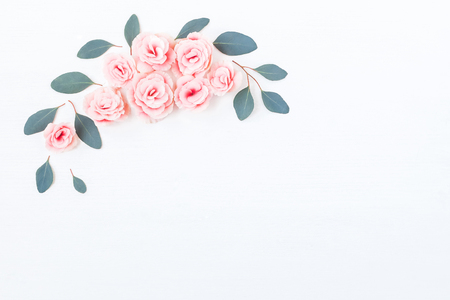 Flowers composition. Frame made of pink rose flowers and eucalyptus leaves on white background. Flat lay, top viewの写真素材