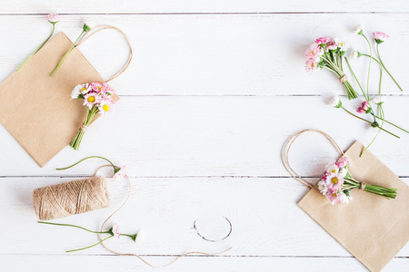 Workspace with small bouquets of daisy flowers, paper bags. Creation. Top view, flat layの写真素材