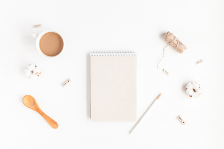 Workspace with notebook, cup of coffee, cotton flowers. Flat lay, top viewの写真素材