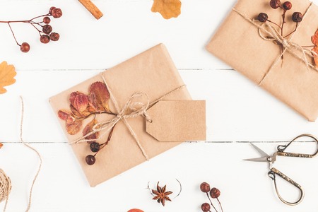 Autumn composition. Gift, autumn leaves, cinnamon sticks, anise star on wooden white background. Flat lay, top view, close up.の写真素材