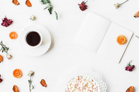 Workspace with notebook, cup of coffee, autumn leaves and dried rose flowers. Top view, flat layの写真素材