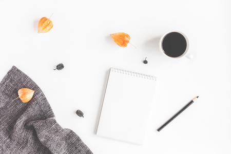 Autumn workspace. Cup of coffee, scarf, notebook, autumn flowers on white background. Flat lay, top viewの写真素材