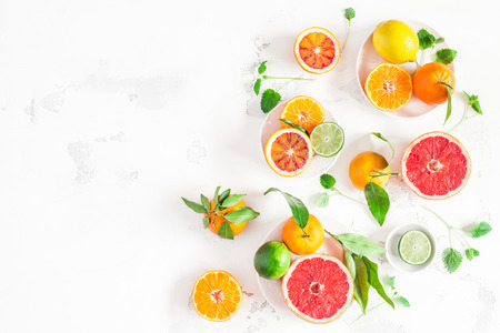 Fruit background. Colorful fresh fruits on white table. Orange, tangerine, lime, lemon, grapefruit. Flat lay, top view, copy spaceの写真素材