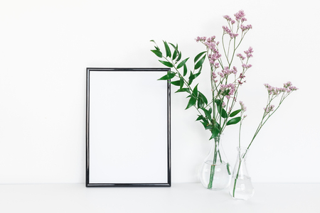 Flowers composition. Photo frame, pink flowers, green leaves on white background. Front view, copy space, mock upの写真素材