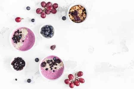 Breakfast with muesli, acai blueberry smoothie, fruits on white background. Healthy food concept. Flat lay, top view, copy spaceの写真素材