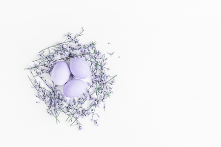 Easter eggs and purple flowers on white background. Easter concept. Flat lay, top view, copy spaceの写真素材