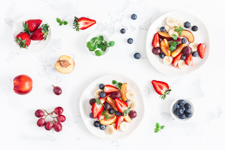 Fruit salad with strawberry, blueberry, peach, banana, grape and fresh fruits on white background. Flat lay, top viewの写真素材