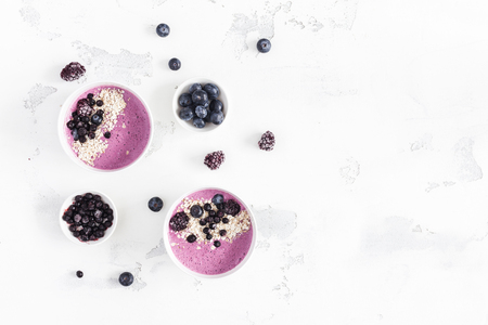 Breakfast with muesli, acai blueberry smoothie, fruits on white background. Healthy food concept. Flat lay, top view, copy spaceの写真素材