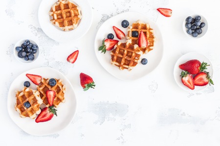 Belgian waffles with fresh strawberry and blueberry on white background. Flat lay, top view, copy spaceの写真素材