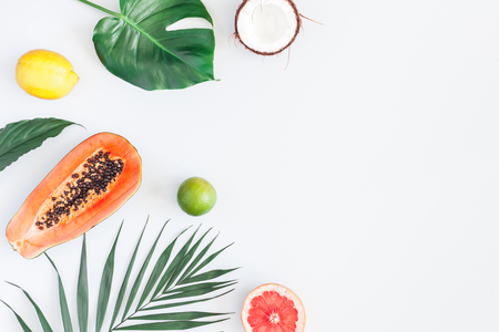 Summer tropical composition. Green palm leaves and tropical fruits on gray background. Summer concept. Flat lay, top view, copy spaceの写真素材