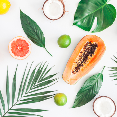 Summer tropical composition. Green palm leaves and tropical fruits on gray background. Summer concept. Flat lay, top view, squareの写真素材