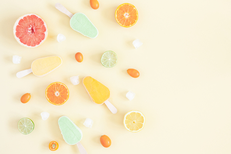 Summer background. Popsicles, colorful fresh fruits on pastel yellow background. Orange, tangerine, lime, lemon, grapefruit. Summer concept. Flat lay, top view, copy spaceの写真素材