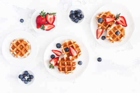 Belgian waffles with fresh strawberry and blueberry on white background. Flat lay, top view, copy spaceの写真素材