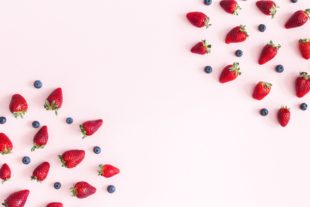 Strawberry and blueberry frame on pastel pink background. Flat lay, top view, copy spaceの写真素材