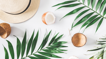 Summer composition. Tropical palm leaves, hat, coconut, pineapple on pastel blue background. Summer concept. Flat lay, top viewの写真素材