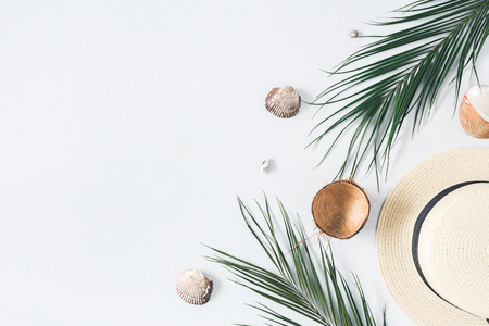 Summer composition. Tropical palm leaves, hat, coconut on pastel blue background. Summer concept. Flat lay, top view, copy spaceの写真素材
