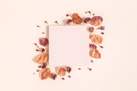 Autumn composition. Paper blank, dried flowers and leaves on pastel beige background. Autumn, fall concept. Flat lay, top view, copy spaceの写真素材