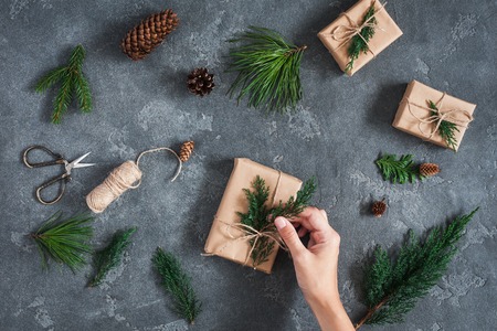 Christmas workspace. Girl's hands making christmas gifts on black background. Flat lay, top viewの写真素材