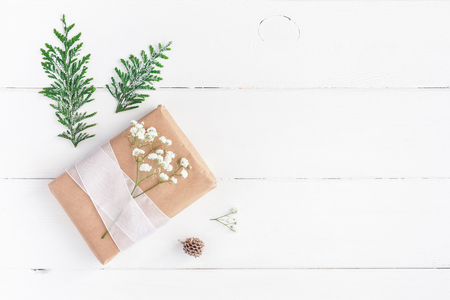 Christmas border. Christmas gift, pine cone, gypsophila flowers, thuja branches on white wooden background. Flat lay, top view, copy spaceの写真素材