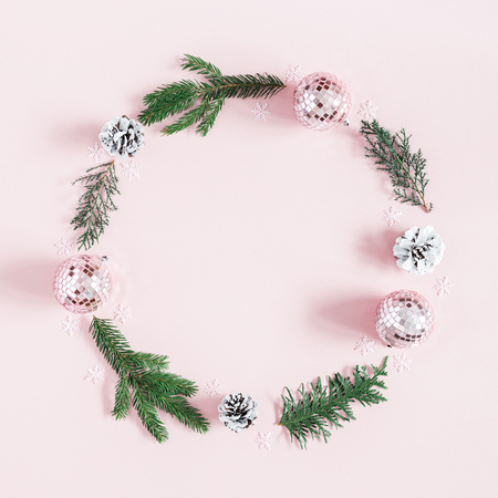 Christmas composition. Wreath made of fir tree branches, pink balls on pastel pink background. Christmas, winter, new year concept. Flat lay, top view, square, copy spaceの写真素材