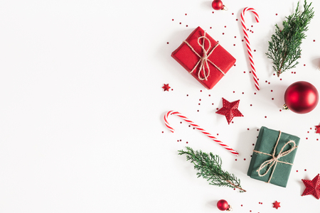 Christmas composition. Gifts, fir tree branches, red decorations on white background. Christmas, winter, new year concept. Flat lay, top view, copy spaceの写真素材