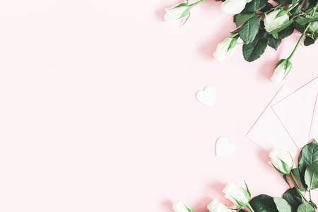 Flowers composition. White rose flowers, envelopes on pastel pink background. Valentines day, mothers day, womens day concept. Flat lay, top view, copy spaceの写真素材