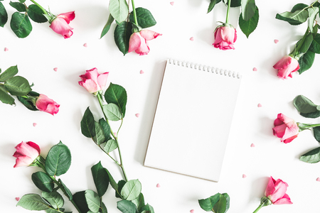 Flowers composition. Pink rose flowers, notebook on white background. Flat lay, top view, copy spaceの写真素材
