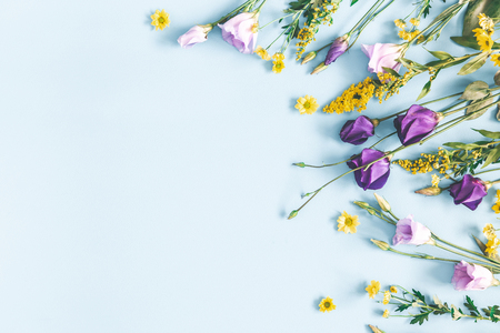 Flowers composition. Yellow and purple flowers on pastel blue background. Spring, easter concept. Flat lay, top view, copy spaceの写真素材