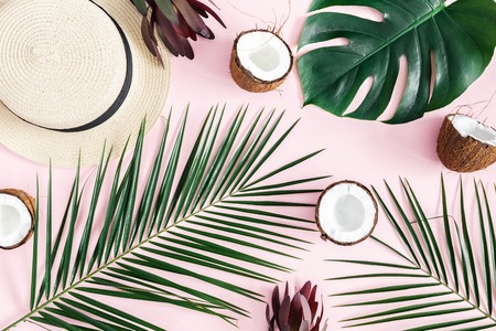 Summer composition. Tropical palm leaves, hat, coconut on pastel pink background. Summer concept. Flat lay, top viewの写真素材