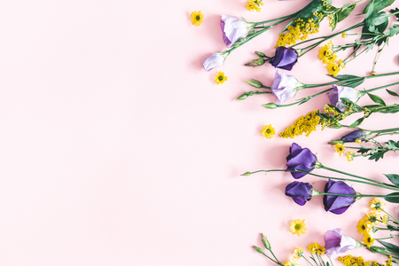 Flowers composition. Yellow and purple flowers on pastel pink background. Spring, easter concept. Flat lay, top view, copy spaceの写真素材