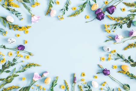 Easter eggs, purple and yellow flowers on pastel blue background. Spring, easter concept. Flat lay, top view, copy spaceの写真素材
