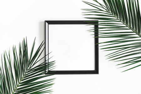 Summer composition. Tropical palm leaves, black photo frame on white background. Summer, nature concept. Flat lay, top view, copy spaceの写真素材