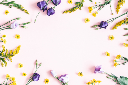 Flowers composition. Yellow and purple flowers on pastel pink background. Spring, easter concept. Flat lay, top view, copy spaceの写真素材