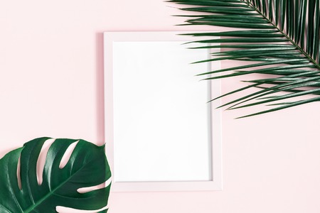 Summer composition. Tropical palm leaves, photo frame on pink background. Summer, nature concept. Flat lay, top view, copy spaceの写真素材