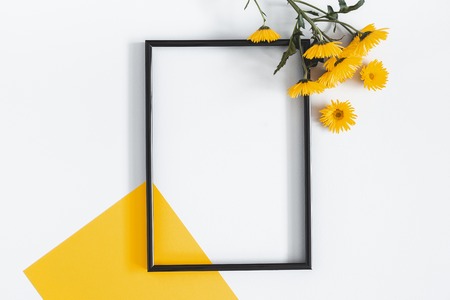Flowers composition. Yellow flowers, photo frame on pastel gray background. Spring, summer concept. Flat lay, top view, copy spaceの写真素材