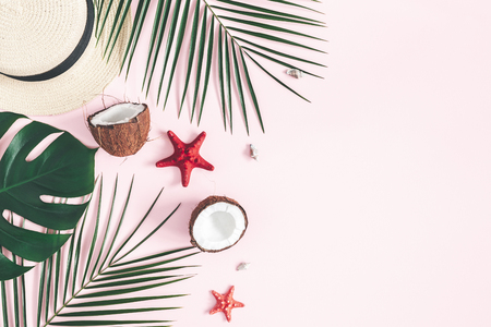 Summer composition. Tropical palm leaves, hat, coconut on pastel pink background. Summer concept. Flat lay, top view, copy spaceの写真素材