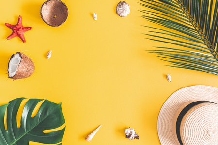 Summer composition. Tropical palm leaves, hat, coconut on yellow background. Summer concept. Flat lay, top view, copy spaceの写真素材
