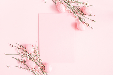Easter composition. Easter eggs, paper blank, white flowers on pastel pink background. Flat lay, top view, copy spaceの写真素材