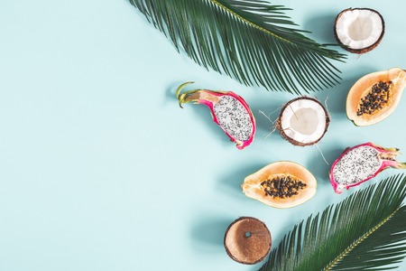 Summer composition. Tropical palm leaves, fruits on blue background. Summer concept. Flat lay, top view, copy spaceの写真素材