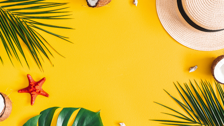 Summer composition. Tropical palm leaves, hat, coconut on yellow background. Summer concept. Flat lay, top view, copy spaceの写真素材
