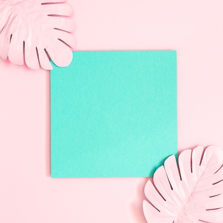 Summer composition. Tropical palm leaves, blue paper blank on pink background. Summer concept. Flat lay, top view, copy space, squareの写真素材