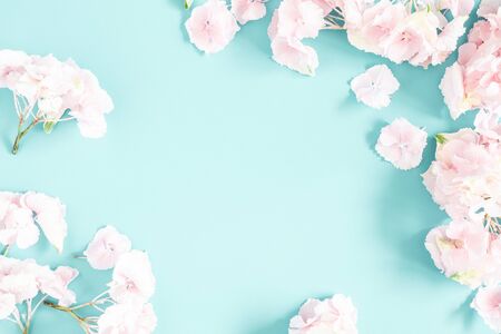 Flowers composition. Frame made of pink and white flowers on pastel blue background. Flat lay, top view, copy space, square