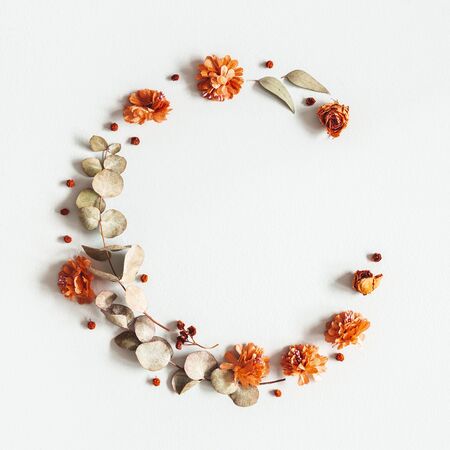 Autumn composition. Wreath made of dried flowers, eucalyptus leaves, berries on gray background. Autumn, fall, thanksgiving day concept. Flat lay, top view, copy space, squareの写真素材