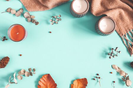 Autumn composition. Candles, scarf, leaves on pastel blue background. Autumn, fall, winter concept. Flat lay, top view, copy spaceの写真素材