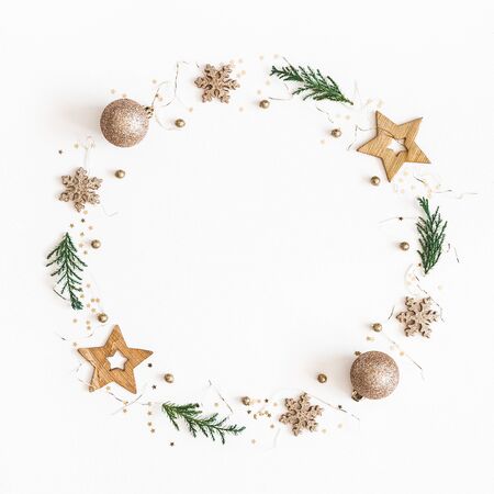 Christmas composition. Christmas wreath made of golden decorations, fir tree branches on white background. Flat lay, top view, copy space, squareの写真素材