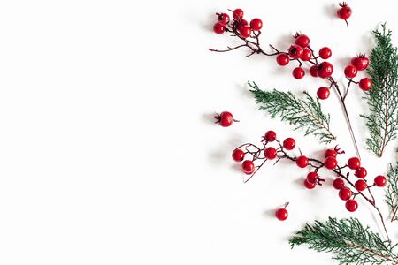 Christmas composition. Pattern made of fir tree branches and red berries on white background. Christmas, winter, new, year, nature concept. Flat lay, top view, copy spaceの写真素材