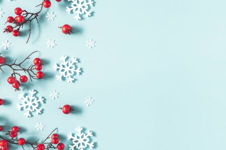Christmas or winter composition. Frame made of snowflakes and red berries on pastel blue background. Christmas, winter, new year concept. Flat lay, top view, copy spaceの写真素材