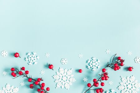 Christmas or winter composition. Frame made of snowflakes and red berries on pastel blue background. Christmas, winter, new year concept. Flat lay, top view, copy spaceの写真素材